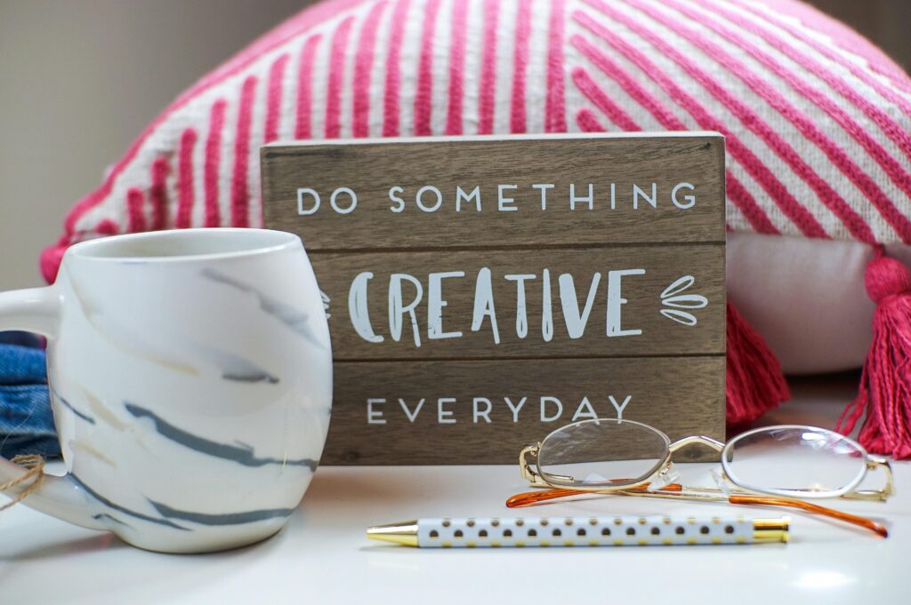 Stylish desk setup with a coffee mug, eyeglasses, and motivating sign.